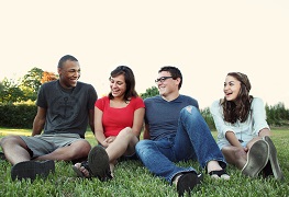 Four youth sitting together in field